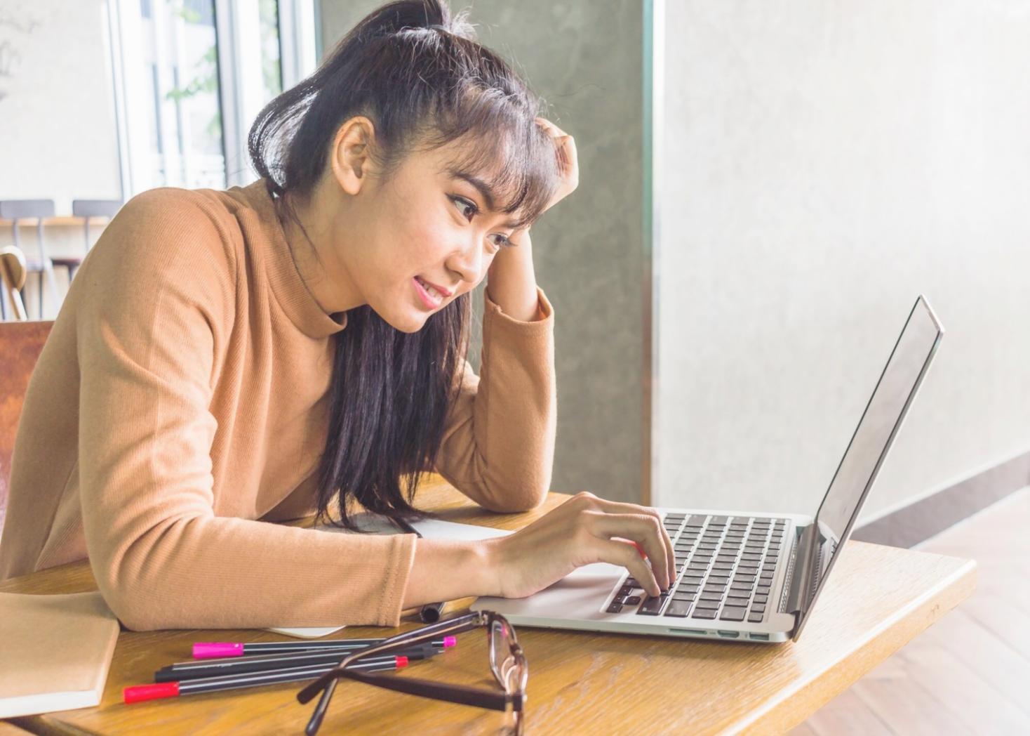 Person reviewing financial documents with laptop showing budget planning spreadsheet